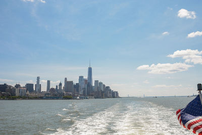 City at waterfront against cloudy sky