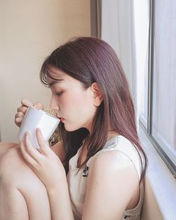 Portrait of young woman drinking drink at home