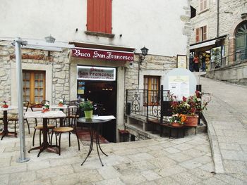 Chairs and tables at sidewalk cafe against buildings in city