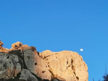 Low angle view of rock formation against clear blue sky