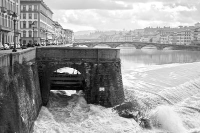 Arch bridge over river against buildings in city