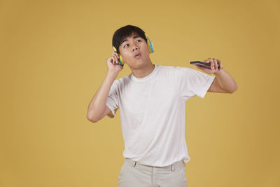 Full length of boy holding yellow against orange background