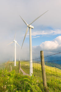 Wind turbines on field against sky