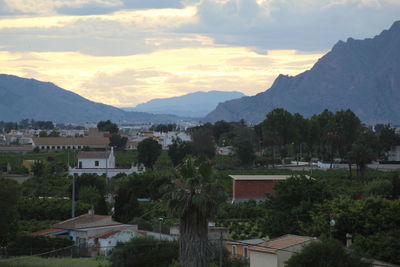 Town by mountains against sky during sunset