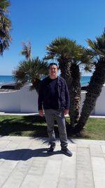 Full length portrait of happy man with umbrella on road