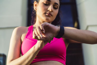Curly young woman, wearing a fitness watch for running.
