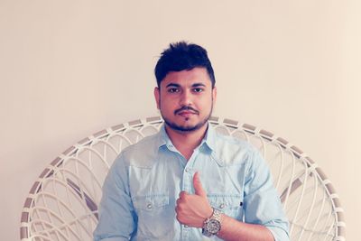 Portrait of a young man in denim shirt with thumbs-up sign