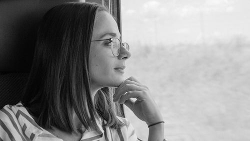 Woman looking through window while traveling in train