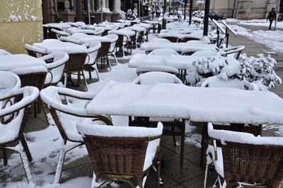 Empty chairs and tables on snow covered table