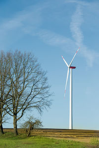 A landscape in the country brandenburg with fields, meadows, trees and a wind turbine.