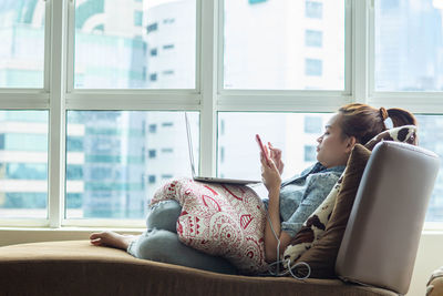 Side view of senior woman sitting on window