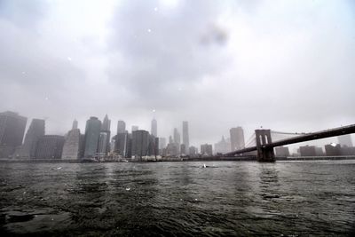 Scenic view of city by river against sky