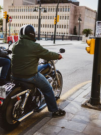 Rear view of man riding bicycle on street in city