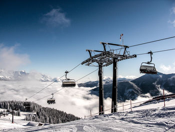 Low angle view of overhead cable car over snow covered landscape against sky