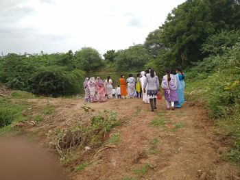 Rear view of people walking on field