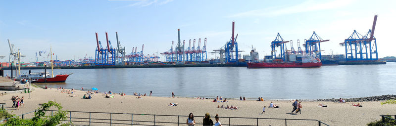 People at beach against cargo containers