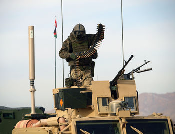 Army soldier holding bullets while standing in armored tank