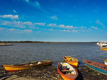 Boats moored in calm blue sea against sky
