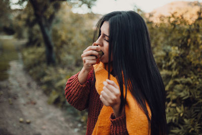 Side view of young woman looking away while standing outdoors