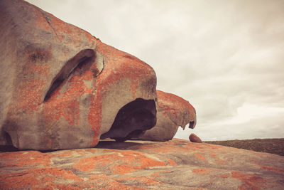 Low angle view of boulder rocks against cloudy sky