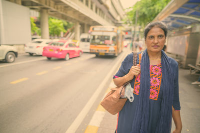 Portrait of man standing on road in city