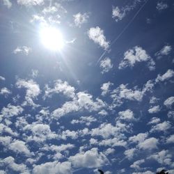 Low angle view of sun shining through clouds