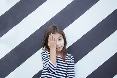 Portrait of young woman standing against wall