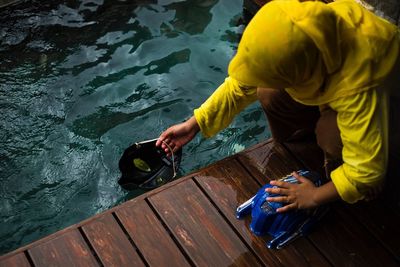 High angle view of child filling water in mask on pier over lake