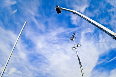 Low angle view of hydraulic platform and floodlight against blue sky