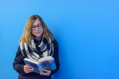 Woman reading book against blue background
