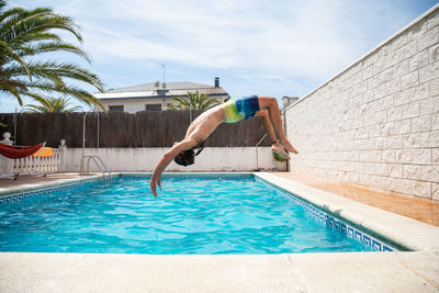 Man jumping in swimming pool against sky