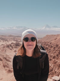 Portrait of young woman wearing sunglasses standing in desert