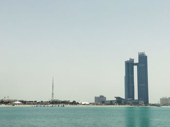 Sea by buildings against clear sky