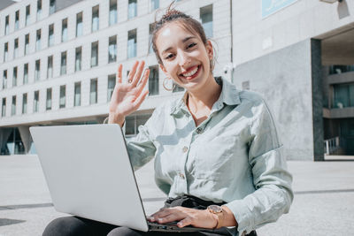 Young businesswoman with laptop sitting outdoors