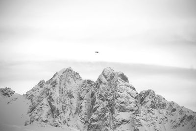 Low angle view of bird flying over mountain against sky