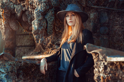 Young woman standing by wall