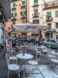 Chairs and tables on street by buildings in city