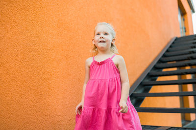 Portrait of young woman standing against yellow wall