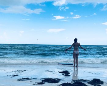 Rear view of man standing on beach against sky