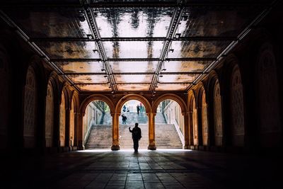 Silhouette man walking under arched ceiling