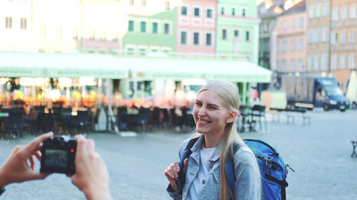 Portrait of smiling young woman using phone in city