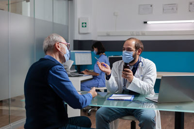 Doctor wearing mask examining senior patient in clinic
