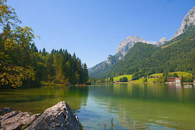 Scenic view of lake and mountains against clear blue sky