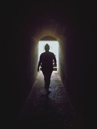 Rear view of silhouette man walking in tunnel