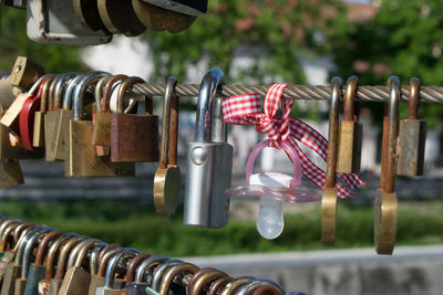 Close-up of padlocks and pacifier hanging on metal rope