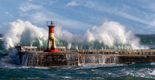 Lighthouse by sea against sky