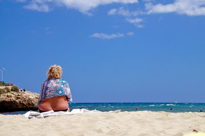 Rear view of woman sitting on beach