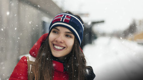 Close-up of smiling woman wearing headband standing outdoors during snowfall