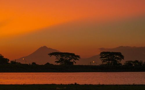 Scenic view of silhouette mountains against orange sky