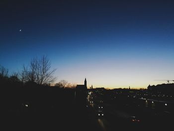 Silhouette city against clear sky at night